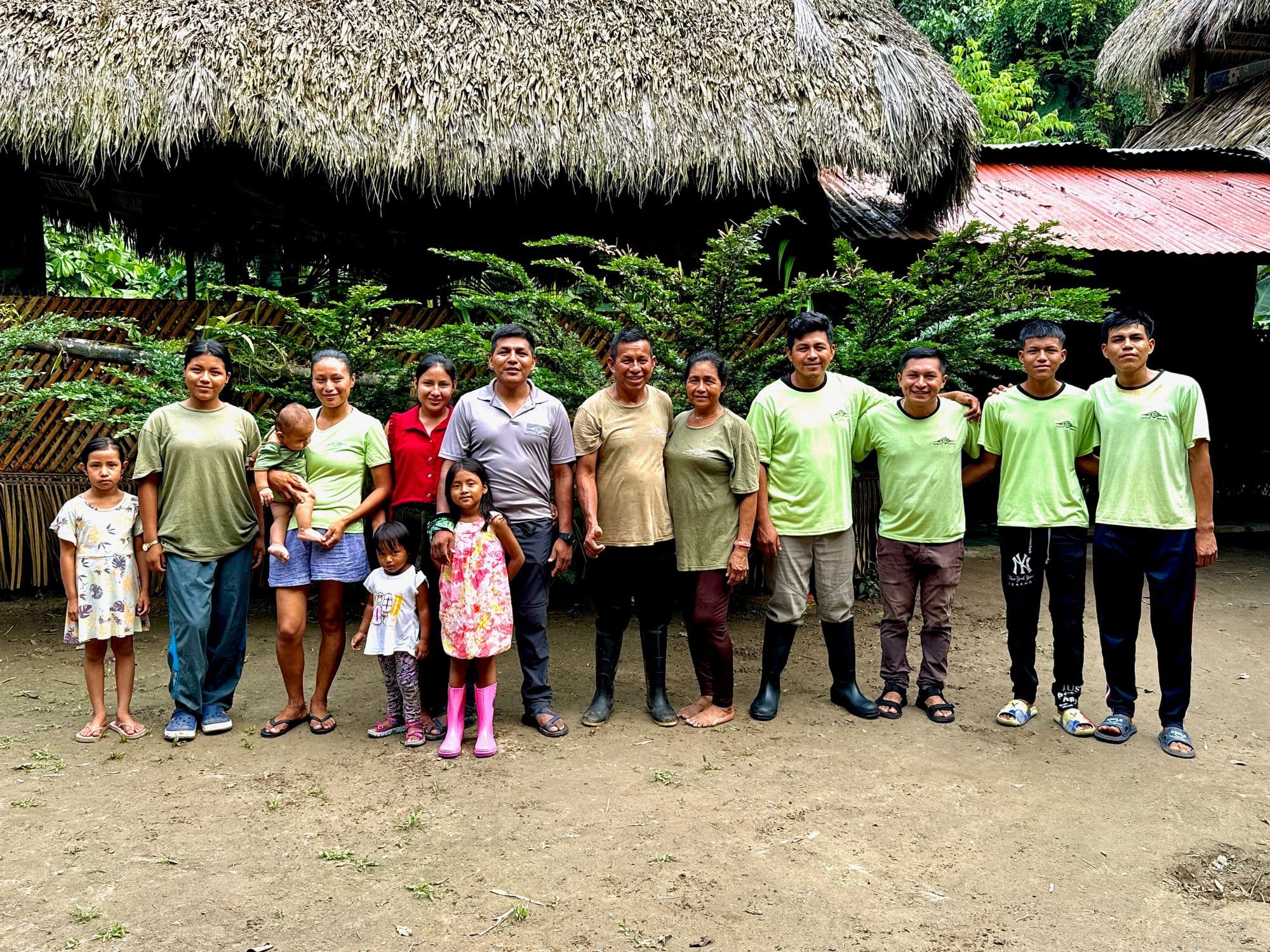 Un retrato grupal de la familia y el personal de Sinchi Wayra posando frente al albergue ecológico en el Amazonas.